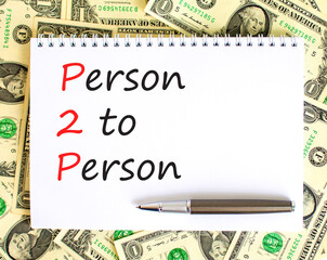 P2P person to person symbol. Concept words P2P person to person on white note on a beautiful background from dollar bills. Pen. Business and P2P person to person concept. Copy space.