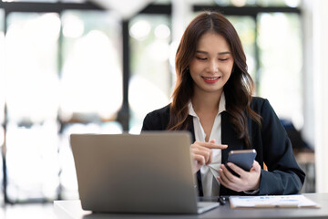Asian businesswoman in formal suit in office happy and cheerful during using smartphone and working
