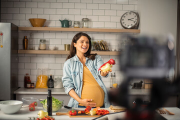 Beautiful pregnant woman filming cooking vlog. Happy woman filming her blog about healthy food at home.