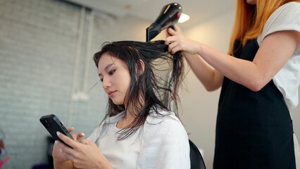 Professional hair stylists using hairspray and use comb to comb woman clients hair in beauty salon