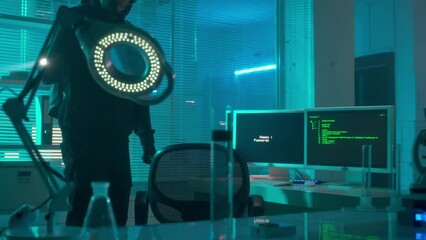 A hacker in a black hoodie and gloves is spying in the laboratory, typing on a computer keyboard. A man downloads a virus to computer and the infection rate starts counting down.
