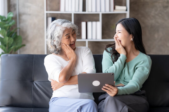 Happy Asian mother and daughter using tablet for video call at home on vacation.