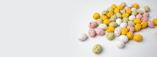 Multi-colored chocolate decorative eggs on a white background. Happy Easter background, web banner. Top view