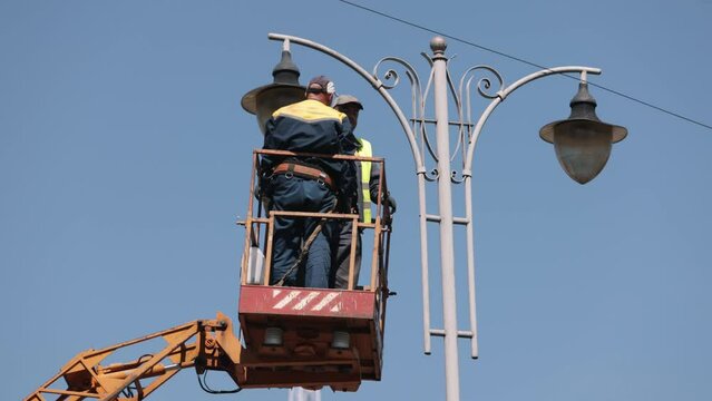Street light, Electric technical, street lamp. Repair work at street light, worker fixing light pole lamp at height, replacement of led lights, workers replacing pole lamp