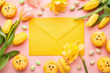 Easter background made of macaroon chicks, yellow tulips and daffodils, candy chocolate eggs and yellow envelope over pink background. Top view, copy space.  Holiday symbol