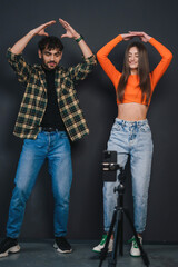 Caucasian couple making dance video challenge on smartphone isolated over black background. Video blogging. Generation Z. Content for social networks