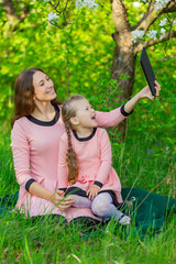 Fototapeta premium mother and daughter take pictures using a tablet in nature