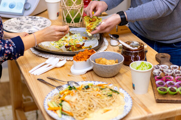 Enjoying dinner with friends. Top view of group of people having dinner together while sitting at the rustic wooden table