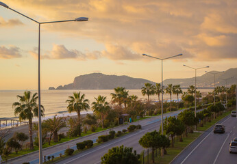 Beautiful photo of Alanya at sunset overlooking the mountain. Warm sunset by the sea next to the road. Warm sunset by the sea
