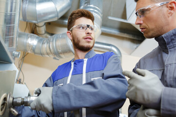 portrait of engineer and apprentice in factory