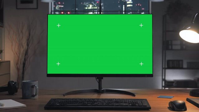 green screen computer on the home desk at night with modern city window in the background,chroma key pc monitor on the office table set up for work,remote working copy space zoom in motion