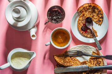 Still life - blueberry jam, green tea and pancakes. Food and drink on a pink background