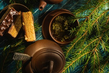 Christmas- still life with a piece of cake and morning tea. Fir tree branches- breakfast on a dark background
