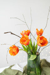 A very beautiful spring bouquet in a green vase stands on a table on a linen tablecloth, orange peony tulips.