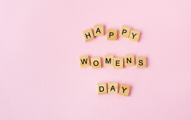 March 8, postcard. Text sign from wooden letters Happy Women's Day on a pink background. Stylish flat lay, greeting card.