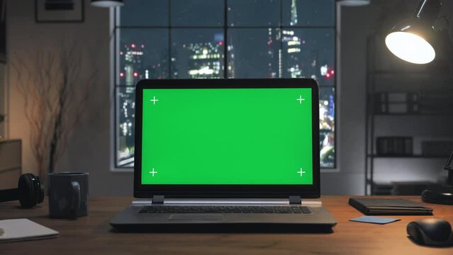 green screen laptop on the home desk at night with modern city window in the background,chroma key computer on the office table set up for work,remote working copy space zoom in motion