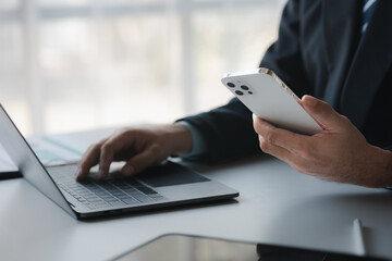 Business man looking at financial information from a mobile phone, he is checking company financial...