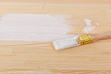 white paint with a brush on a wooden background with texture