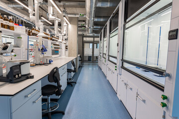 Chemistry lab with white cabinets, chemist workstations and swivel castor chairs. High room....