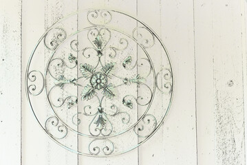 tinted green round metal ornate artwork against wooden wall 