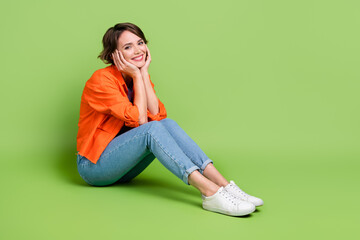 Full length photo of dreamy sweet woman wear denim jacket hands arms cheeks cheekbones empty space isolated green color background