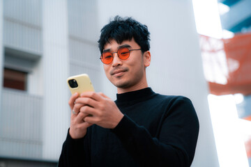 young asian man wearing red cool glasses with smartphone gesture of happiness smiling life style