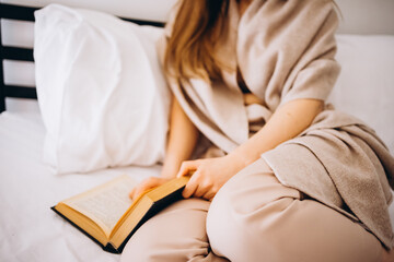 the girl is reading a book on the bed. a mood of pacification and peace