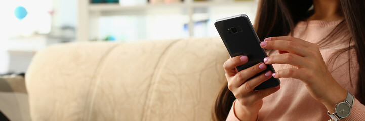 Woman using smartphone sitting on sofa at home