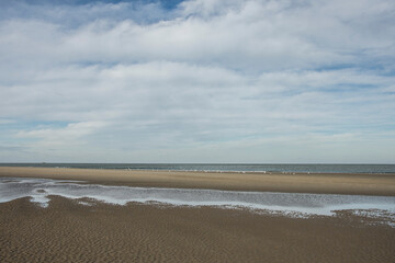 sandbanks in the water of the Northsea coast under a clouded, high sky in winter
