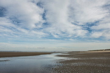 sandbanks in the water of the Northsea coast under a clouded, high sky in winter