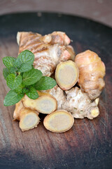 closeup the ripe sliced brown ginger with green mint on the wooden background.