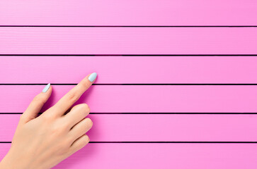 Female hand pointing on pink background