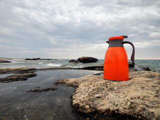 Orange thermos on the shore.