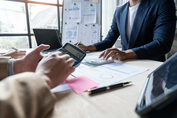 Teamwork of asian business people discussing and calculating with calculator on evaluation data in conference room. with the growth and pointing to the chart graph financial account.