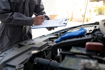 Maintenance engineer or auto mechanic checking car database usage history Enter the details in the file and in the notebook computer. Car maintenance service, mileage check.