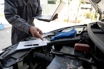 Maintenance engineer or auto mechanic checking car database usage history Enter the details in the file and in the notebook computer. Car maintenance service, mileage check.