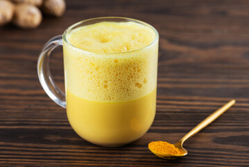 Vegan whipped turmeric golden latte from almond milk, ginger, turmeric and cinnamon in mug.