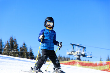 Fototapeta na wymiar Little boy skiing on ski slope in ski resort
