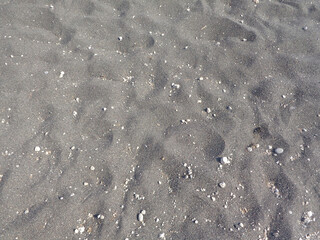 Bakckground of black sand footprints with little rocks