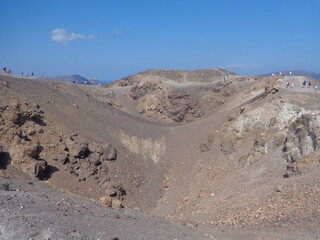 People visitng Santorini volcano crater with a blue sky day.