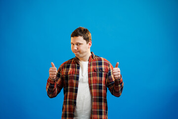 Young handsome man wearing casual shirt over blue background approving doing positive gesture with hand, thumbs up smiling and happy for success. Winner gesture.