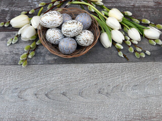 Obraz na płótnie Canvas Korb mit Ostereiern, Weidenkätzchen, und Tulpen auf einem rustikalen Holz Hintergrund dekoriert.