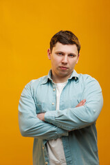 Portrait of handsome european man in shirt looking at camera standing on yellow studio background