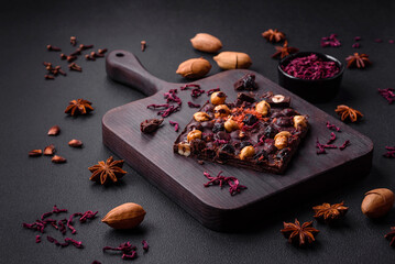 Handmade chocolate with berries, nuts and spices on a dark background