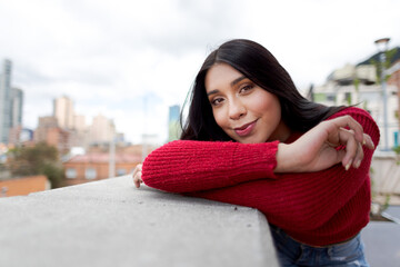 Portrait young latin woman dressed in red beautiful smile, cityscape in the background