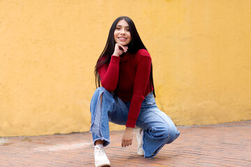 A Casual and Modern Young Woman in an Intense Red Jacket and Blue Jeans on a Yellow Blurred Background