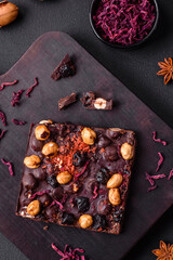 Handmade chocolate with berries, nuts and spices on a dark background