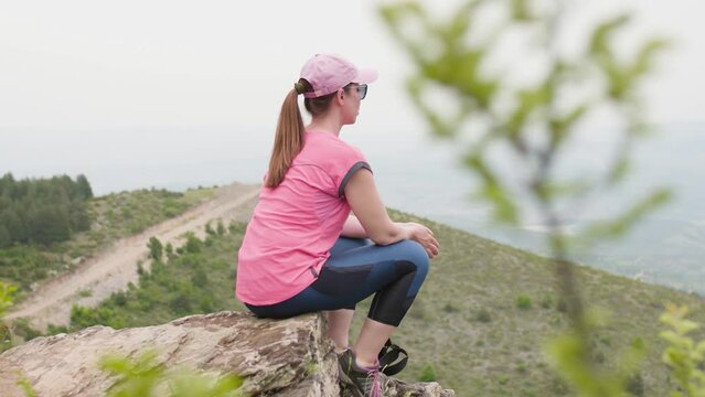 Hiker girl in nature. Taking a break sitting on a rock with a beautiful view.