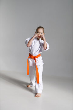 A little karate girl in a white kimono in a fighting stance.