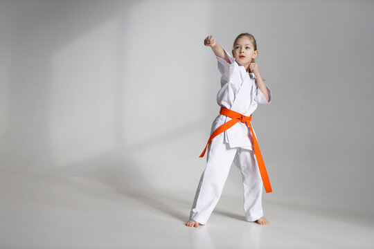 Hand punch in karate, a girl in a kimono on a white background.